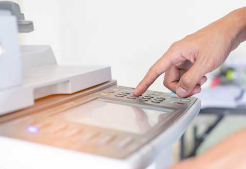 Printer on desk with person person interacting with it