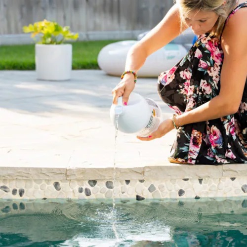 a woman pours liquid shock into her pool