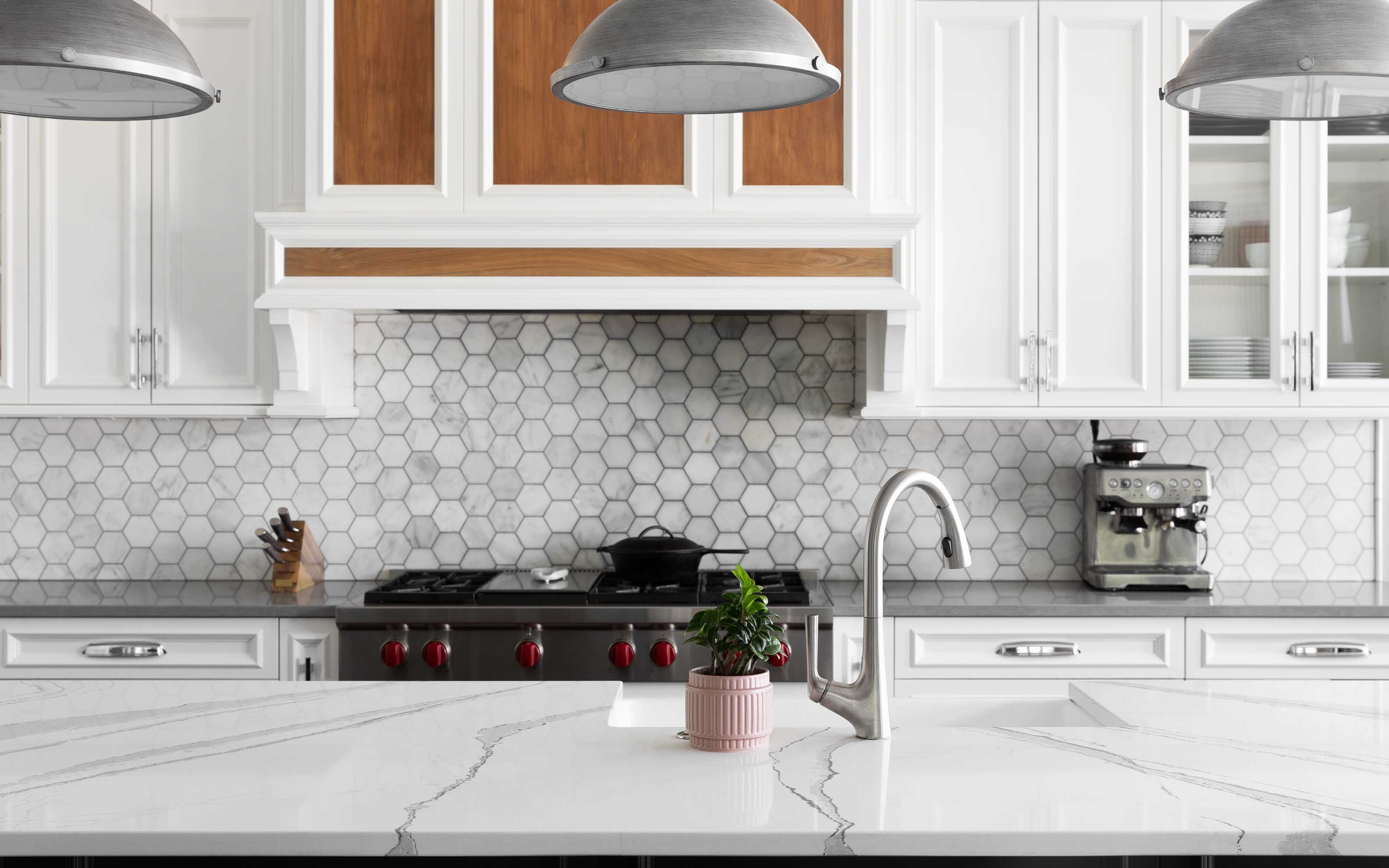 Contemporary Kitchen with Industrial Touches Modern kitchen with white cabinetry, gray hex tile backsplash, marble countertops, and industrial pendant lights above a central island.