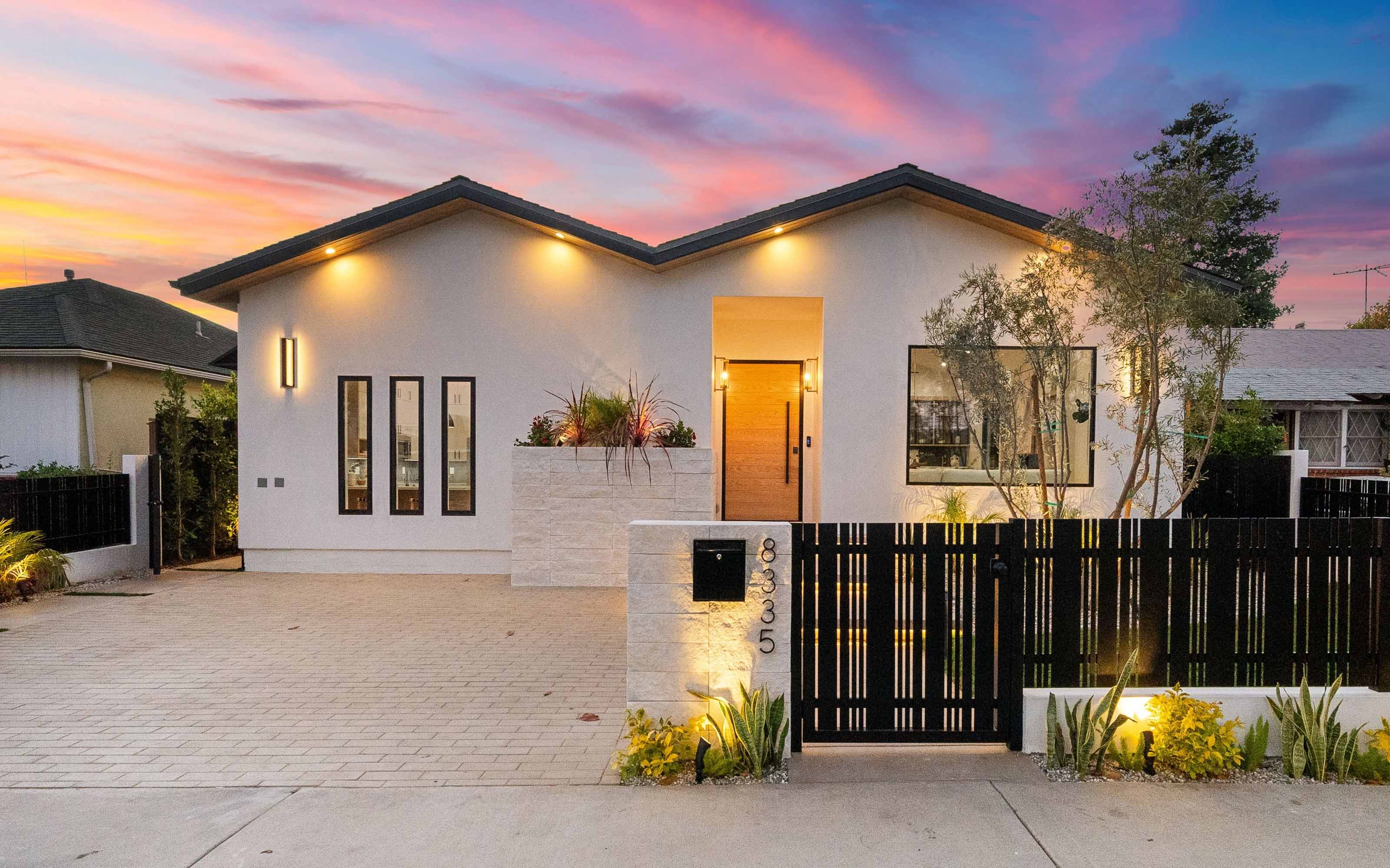 Modern single-story home with updated windows, stylish exterior lighting, and enhanced curb appeal at sunset.