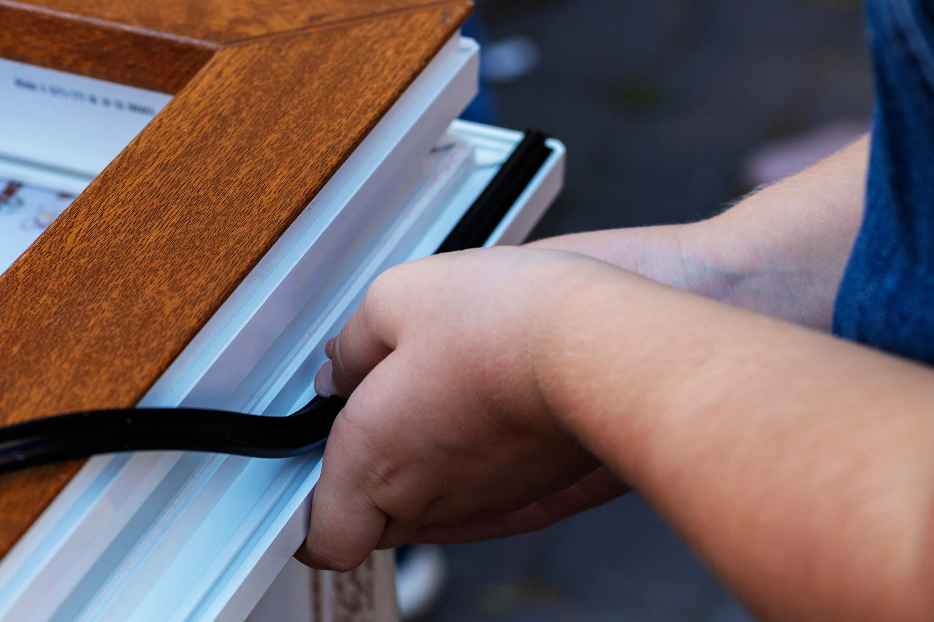 Installing a Rubber Seal Person installing a rubber seal on a wooden frame
