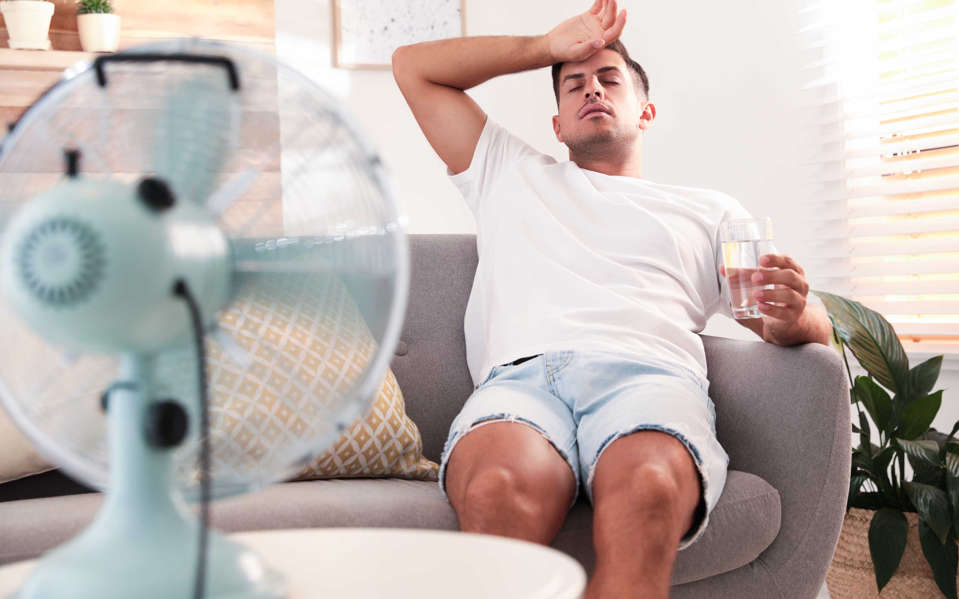 person feeling hot at home due to inefficient old windows and poor insulation