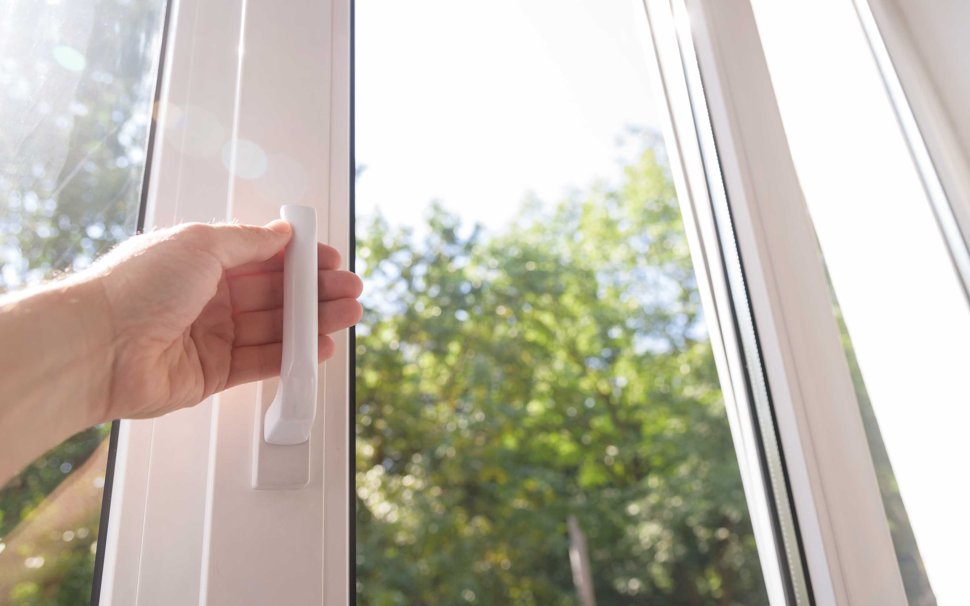 hand opening vinyl window with natural sunlight and outdoor view