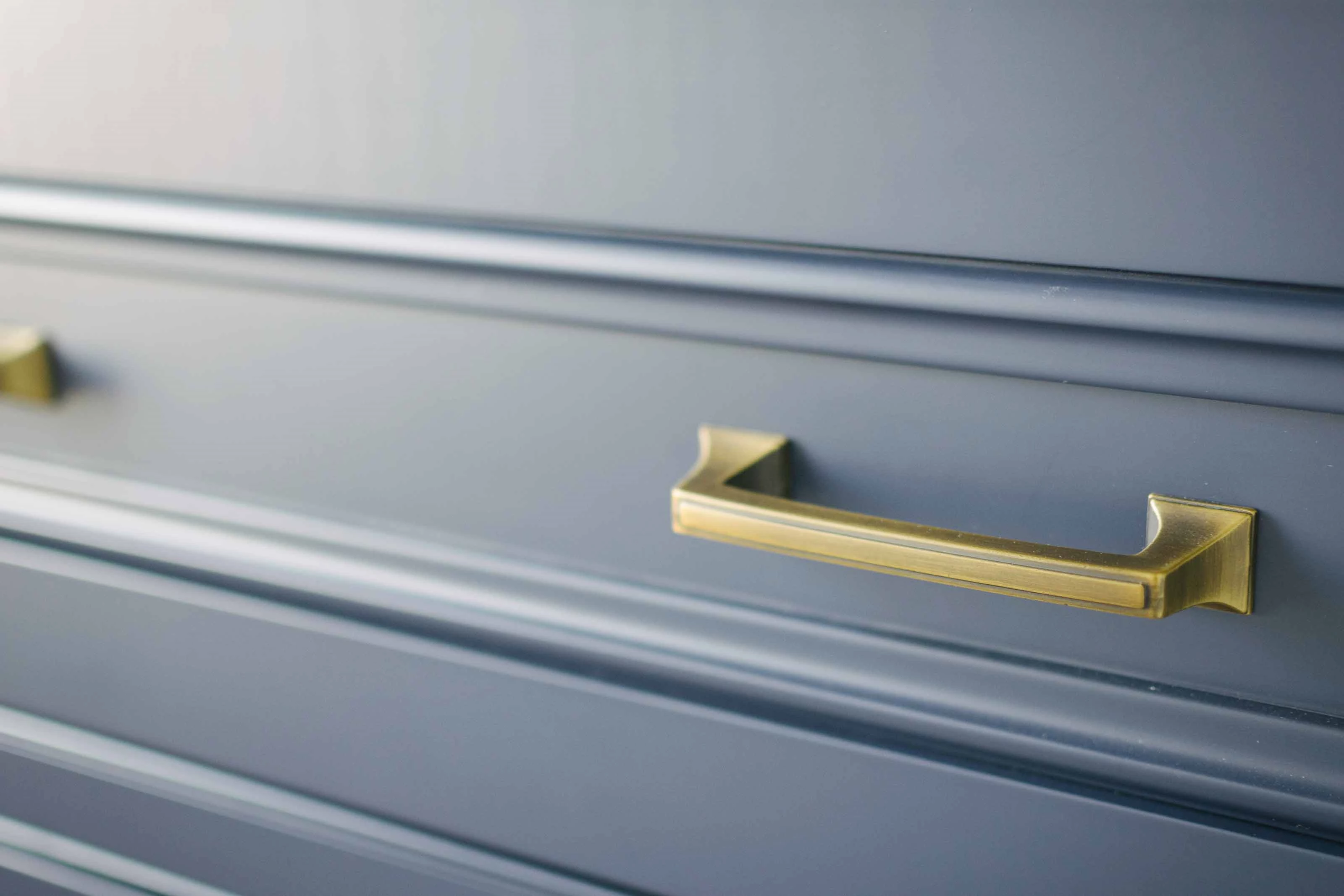 Silver Blue Cabinet with Gold Handles A close up view of a silver blue cabinet with gold handles