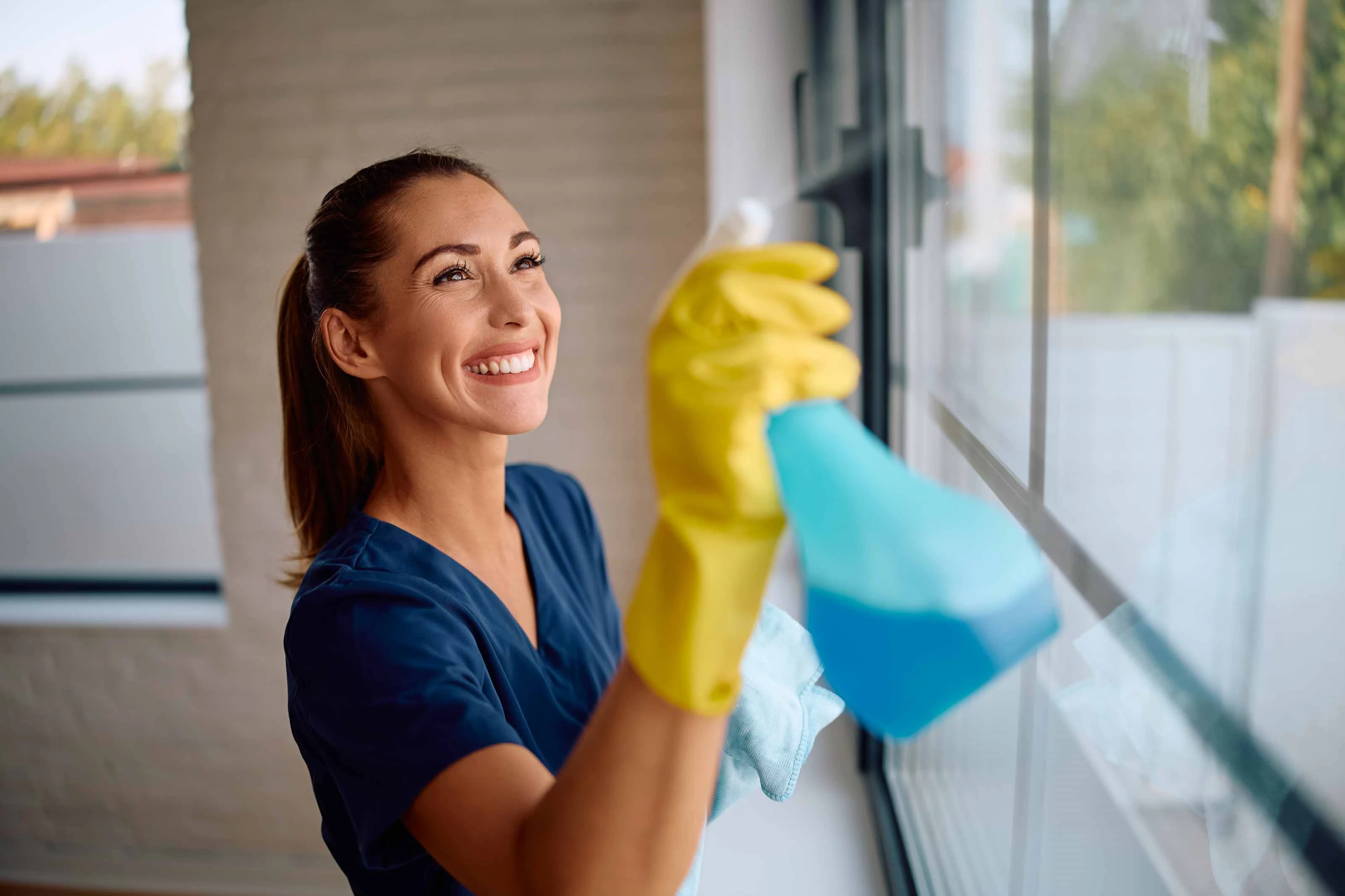 Window Cleaning with Spray Bottle and Cloth a girl wearing a yellow rubber gloves is cleaning a window with a blue spray bottle and a cloth