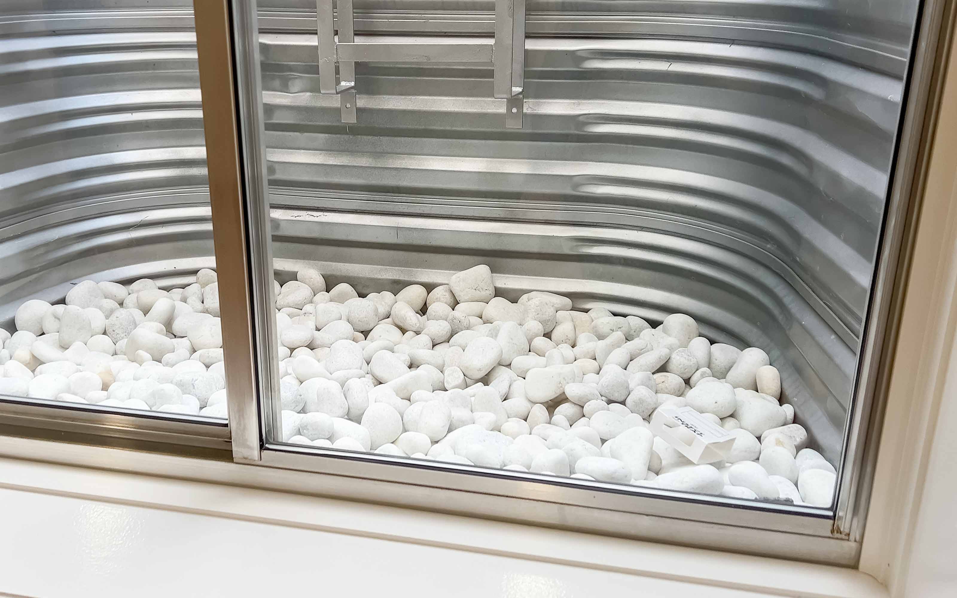 Basement egress window with metal window well and drainage rocks
