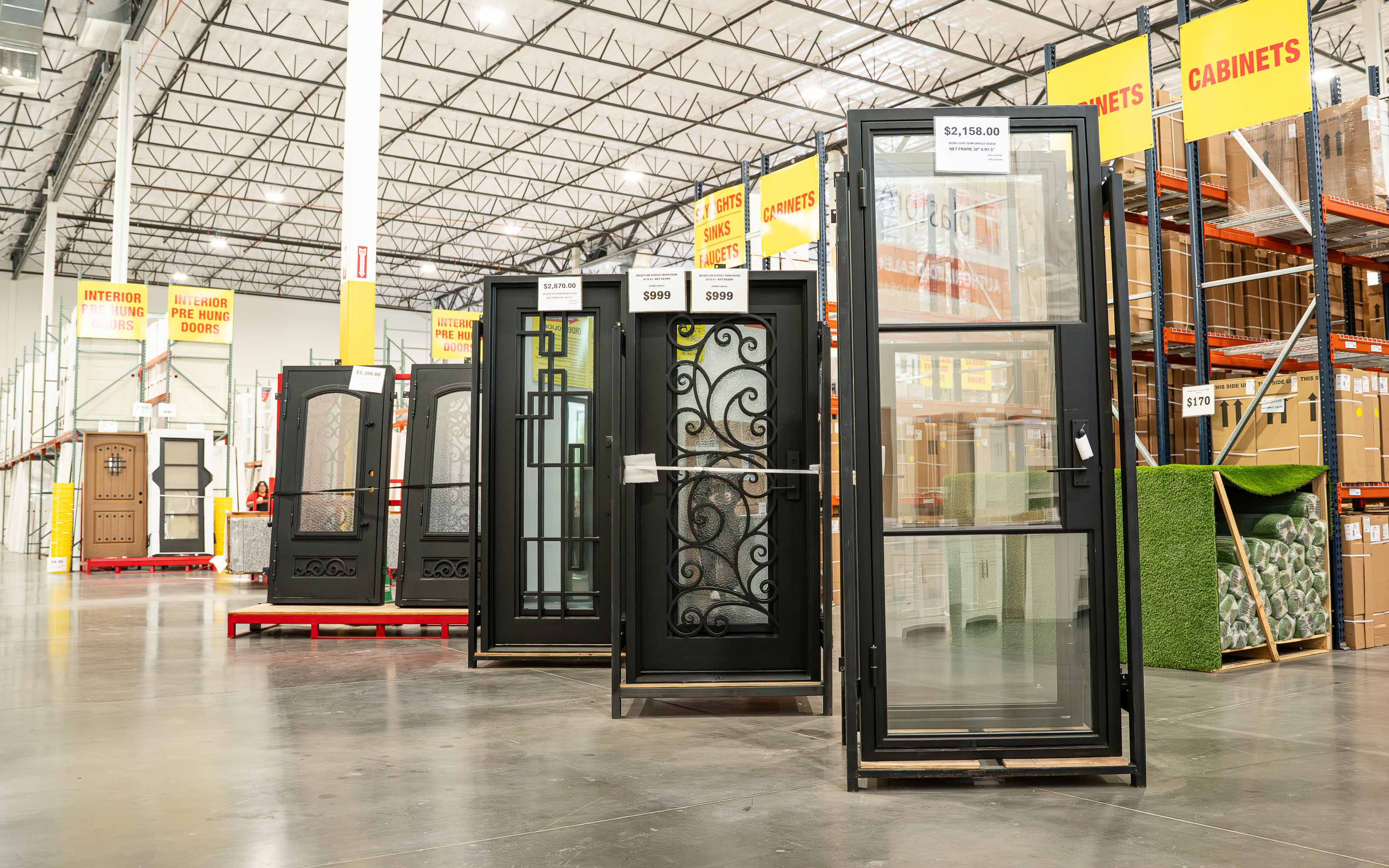 Window and door showroom featuring energy-efficient replacement windows and entry door displays in a home improvement warehouse