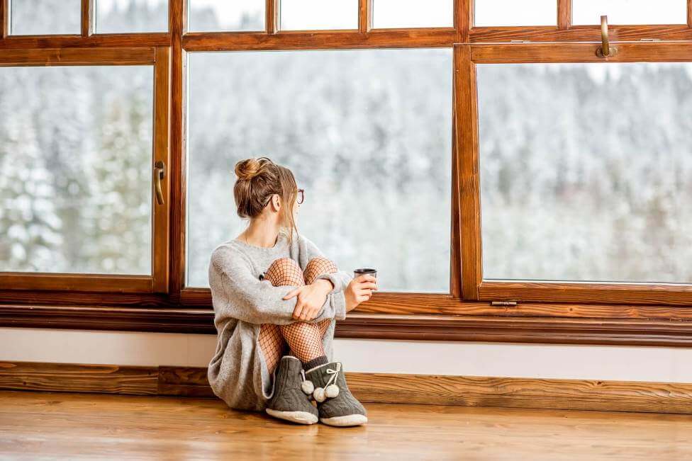 Expert Tips for Choosing Green, Energy-Efficient Windows for Your Home a girl holding coffee mug and looking out of the energy efficient window