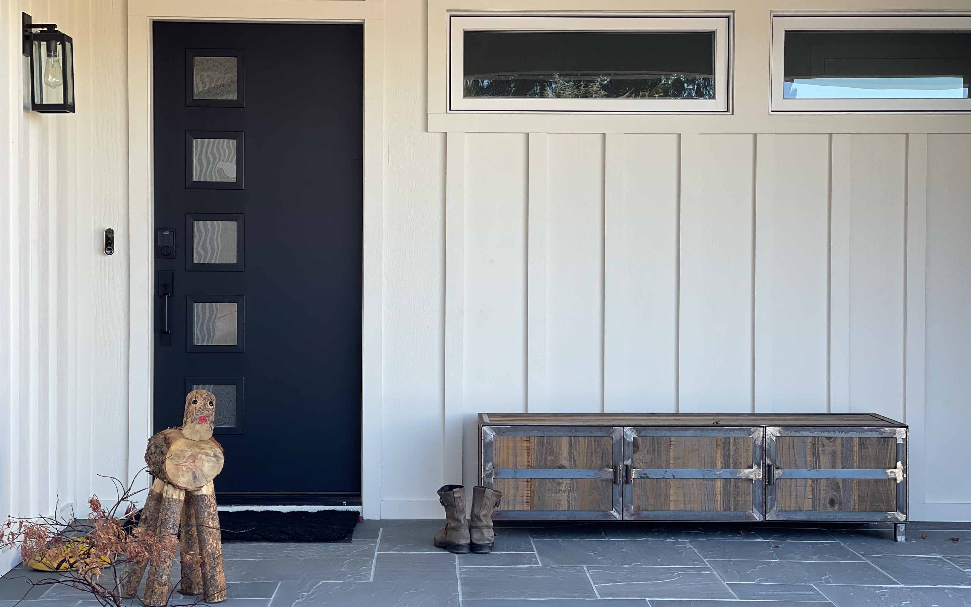 Modern front entry door with white board and batten exterior siding and bench seating on a residential home