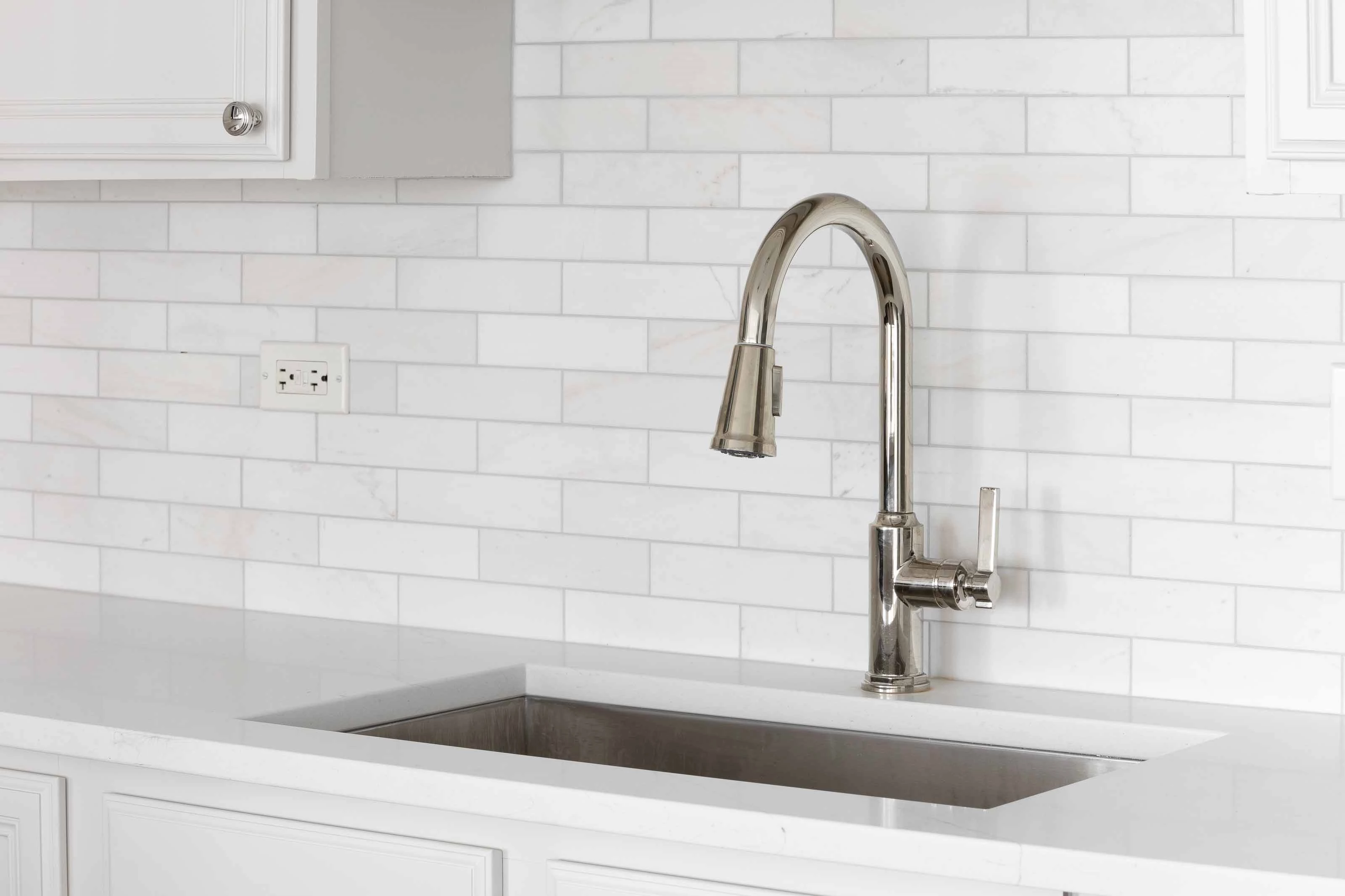 Contemporary Kitchen Sink with Stainless Steel Faucet Modern kitchen sink with a stainless steel faucet against a white subway tile backsplash.